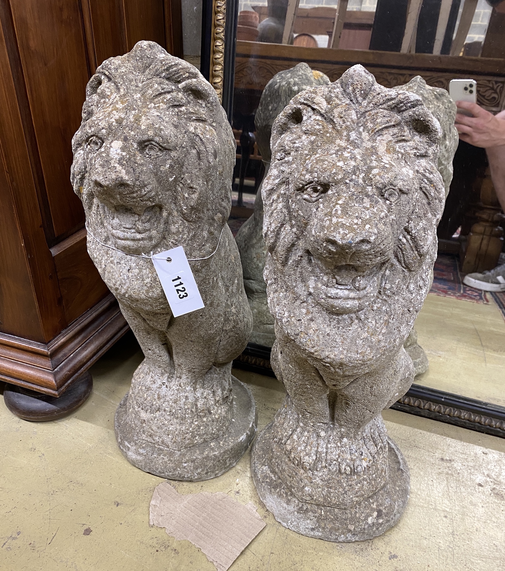 A pair of reconstituted stone seated lion garden ornaments, height 50cm